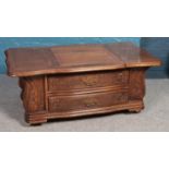 An oak coffee table/entertainment table with two drawers, CD racks to the side and sliding top.