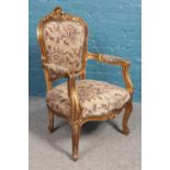 A gold painted throne chair, with floral upholstery to the seat pad, back and arm pads. Height: 99cm