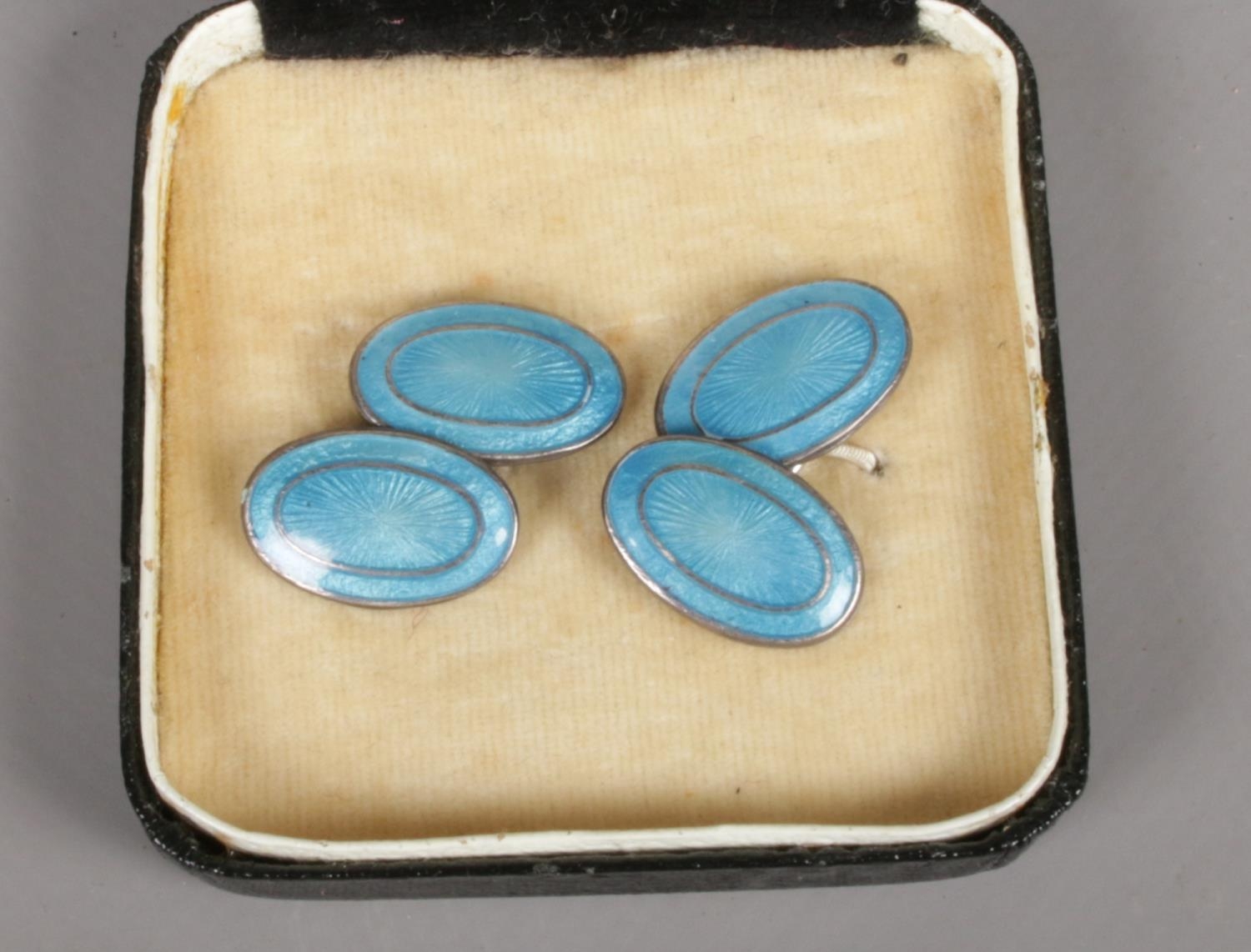A pair of silver cufflinks with blue enamel decoration. Minor scratches to enamel.