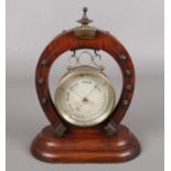 A barometer in cylinder case supported on a horse shoe stand with metal mounts. Maker Curtis of
