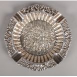 An ornate white metal ashtray. With embossed scene depicting soldiers and pierced border. Stamped