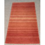 A striped 100% wool rug. L: 150cm, W: 80cm. Mostly in terracotta and cream colour.