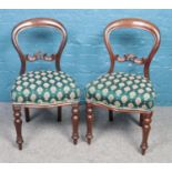 A pair of mahogany balloon back chairs, with green and gold fabric upholstered seat pads.