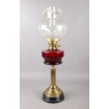 A Duplex glass oil lamp on a black porcelain base. To include a ruby red glass reservoir with