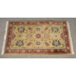 An Indian olive ground wool rug with red border. With central medallion motif. (161cm x 95cm)