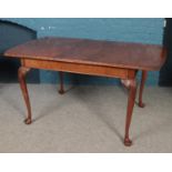 A walnut extending dining table with extra leaf. Raised on carved cabriole legs.