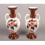 A pair of late Victorian/early Edwardian Longton Derby twin handled urns. Produced by Holmes and Son