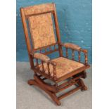 A carved and upholstered American rocking chair with turned supports.