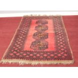 A red ground Aztec style rug. With repeating pattern border. 101cm x 167cm
