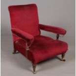 A Howard and Sons Ltd upholstered armchair. Comprising of a mahogany frame on turned front legs