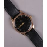 A gents 9ct gold Smiths De Luxe manual wristwatch on leather strap. With baton markers and black