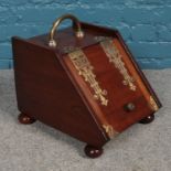 An oak and brass coal scuttle. Comprising of a sloped front with decorative brass hinges and bun