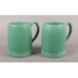 A pair of Wedgwood Keith Murray ceramic tankards in matt green. Signed to the base.