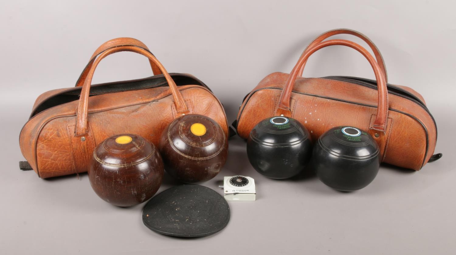 Two pairs of crown green bowls, in travel bags. Also includes a set of measures and foot mat.