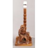 An extensively carved table lamp with turned column, depicting an owl perched on a log. Signed R.