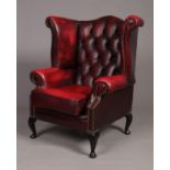 An ox blood deep buttoned studded leather Chesterfield wing back armchair.