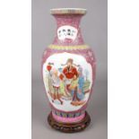 A Chinese famille rose baluster vase on carved wooden stand. Height of vase 35cm.