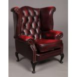 An ox blood deep buttoned studded leather Chesterfield wing back armchair.