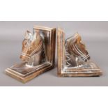 A pair of carved hardwood bookends, depicting horses heads.