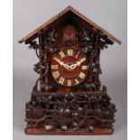 An extensively carved Black Forest cuckoo clock, decorated with vines and berries. Height 34.5cm.