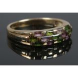 A 9ct Gold band, with emerald and amethyst coloured stones in a chequered strip. Size O. Total