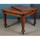 An oak wind out dining table, with additional leaf and winder, raised on casters. Dimensions closed: