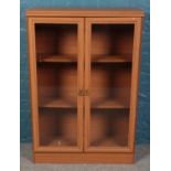 A modern oak veneer bookcase with glass doors. (120cm x 81cm)