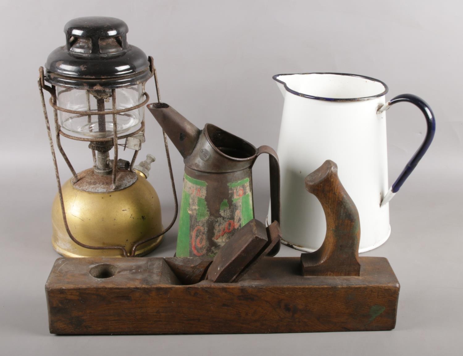 An assortment of items to include Tilley lamp, Castrol can, wood plane and an enamel jug.