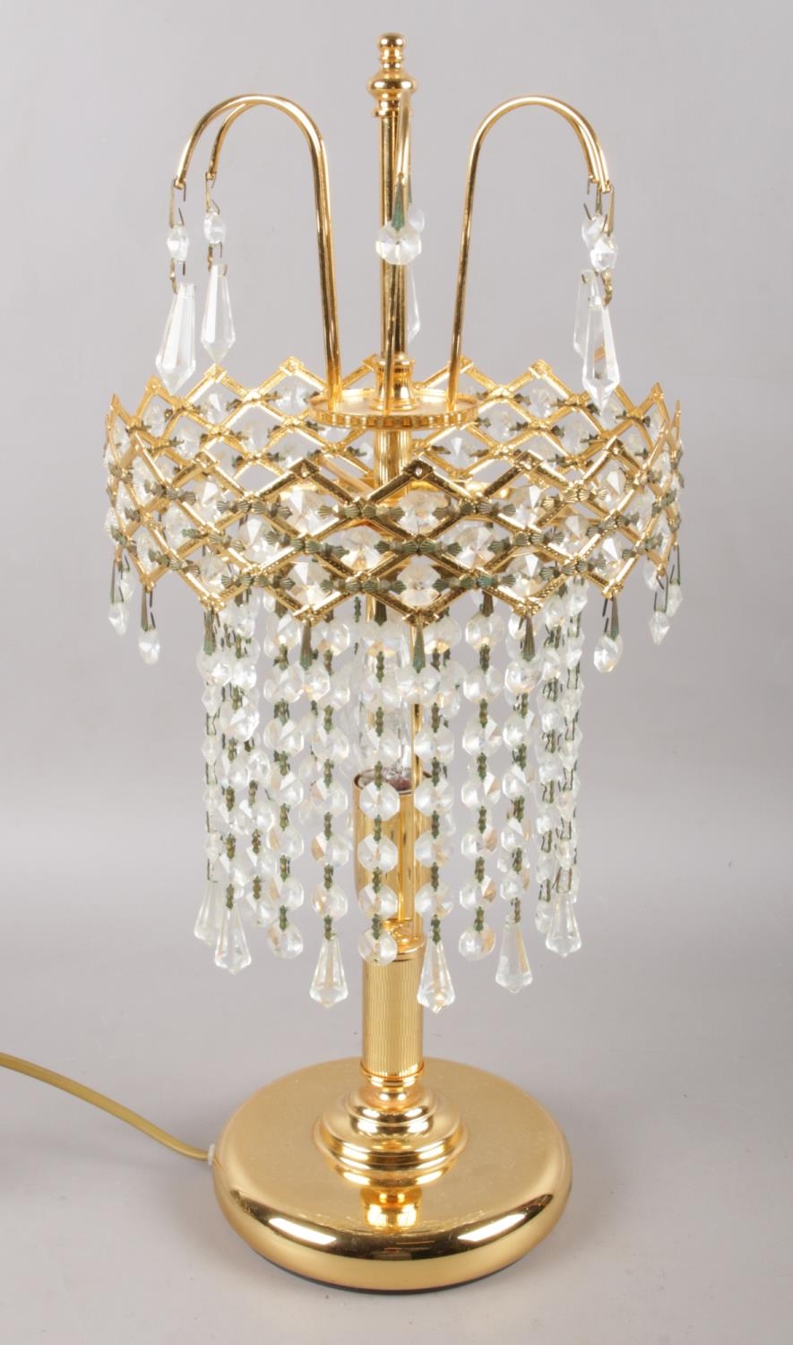 A modern gold coloured table lamp, with a chandelier droplet style shade. In working order.