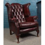 An ox blood buttoned studded leather Chesterfield wing back armchair. Wear to the leather.