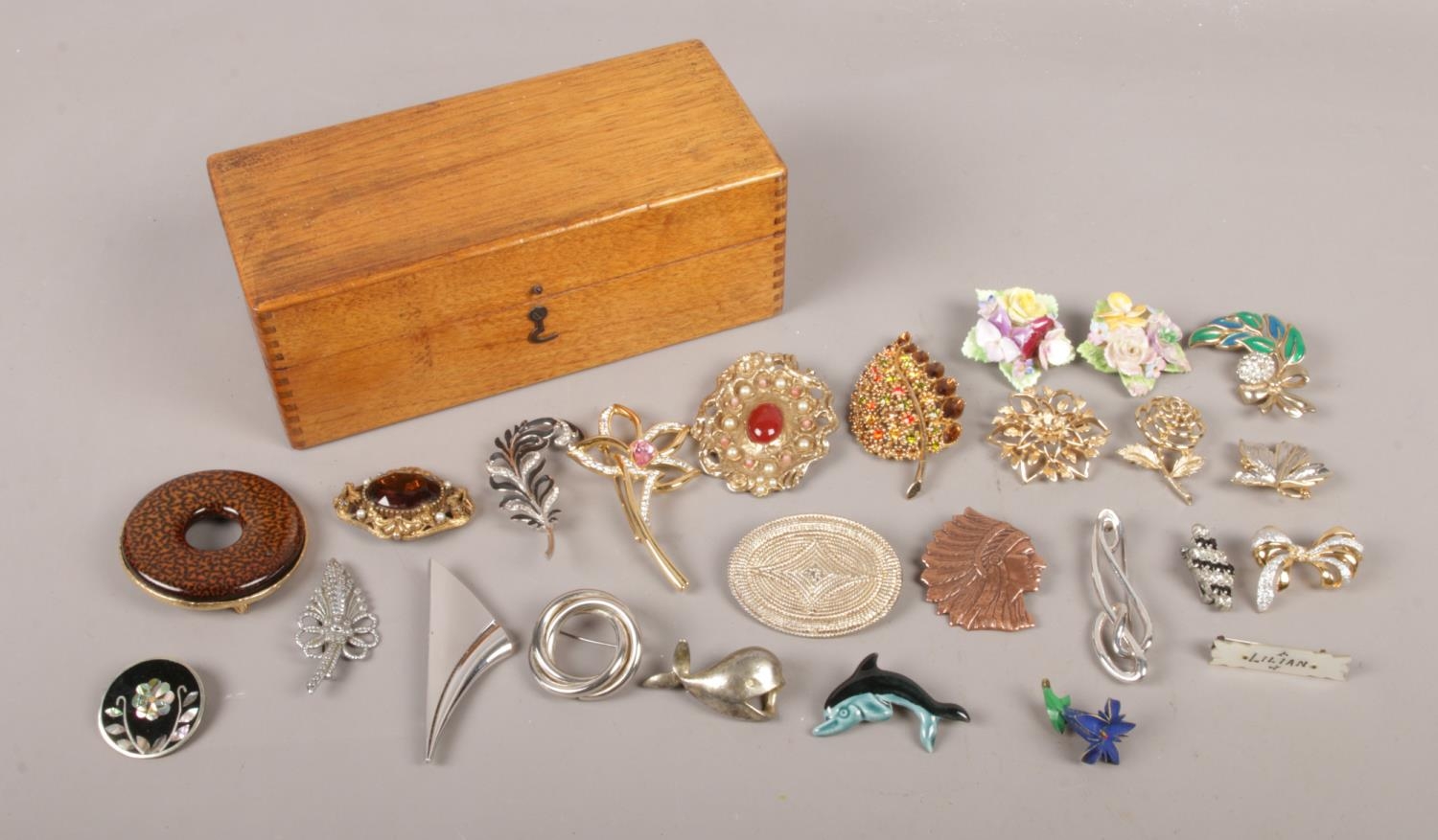 A small wooden box containing twenty five costume brooches.