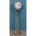 A brass standard lamp with glass dome floral decorated shade.