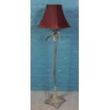A brushed metal standard lamp with red shade.