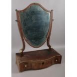 A Regency mahogany toilet mirror, formed as a shield, mounted above three lower drawers. In need