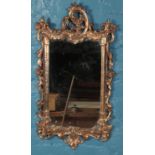 An ornate gilt framed wall mirror. (78cm x 42cm) Generally good condition.