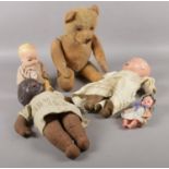 A vintage jointed teddy bear along with four vintage dolls.