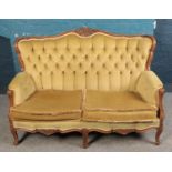 A green deep buttoned upholstered two seat sofa. Decorated with carved frame.