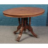 A walnut tilt-top table, with central inlay decoration, carved feet raised on casters. Height: 68cm,