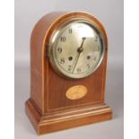 An Edwardian mahogany dome top mantel clock with shell patera inlay decoration.