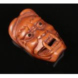 A carved boxwood netsuke formed as a mask. Length 5.5cm.