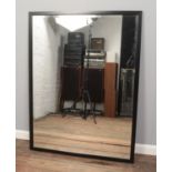 A large modern bevel edged mirror with black frame. 128cm x 97cm.