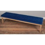 A large deep buttoned bench, upholstered in blue fabric. Width: 180cm