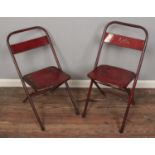Two vintage metal folding chairs with red enamel.