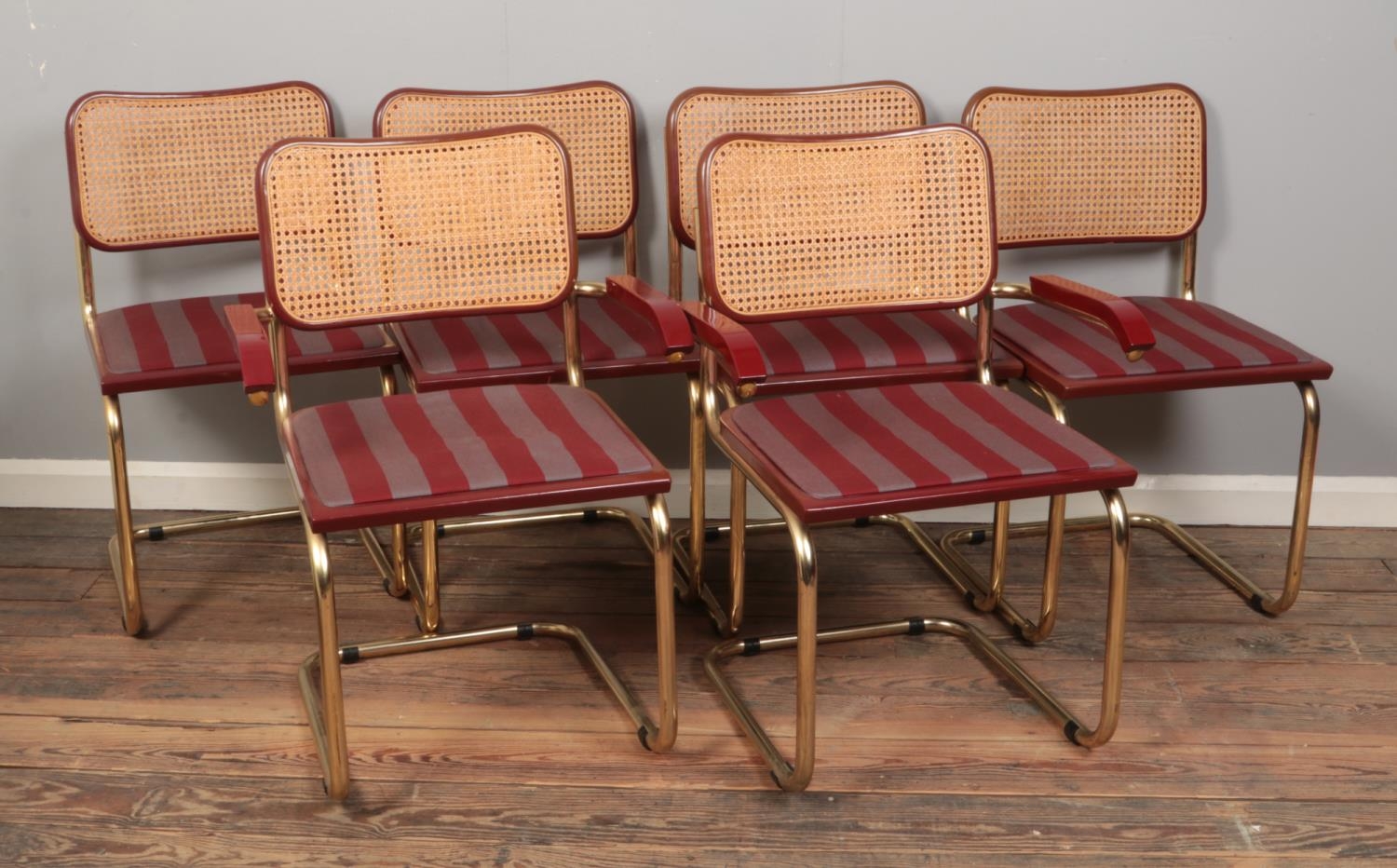 A set of six Marcel Breuer style Cesca chairs with brass coloured tubular frame and maroon striped