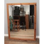 A large pine framed bevel edge mirror. H: 135cm W: 104.5cm.