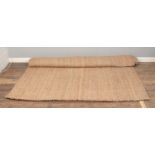 A large seagrass/hessian rug. (297cm x 199cm). Mark to one side of rug.