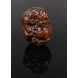An extensively carved boxwood netsuke, formed as temple lion holding a ball. Length 6cm.