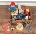 A box of miscellaneous. Includes novelty pig money bank, Paddington bear, Lady Penelope annual etc.