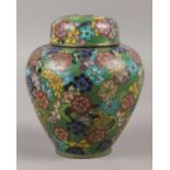 A 19th Century small lidded cloisonne jar, on green foliage background depicting flowers. Blue