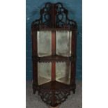 An extensively carved Victorian mahogany hanging corner display unit, with galleried edge and